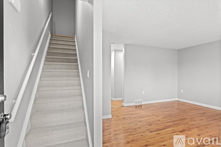 A staircase with a carpeted runner leads to an empty room with wooden floors.
