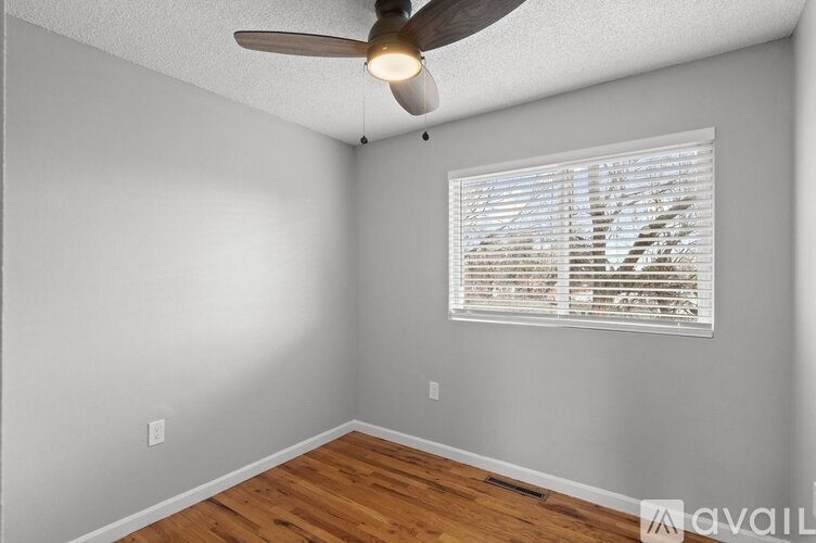 A room with a ceiling fan and a window with blinds.