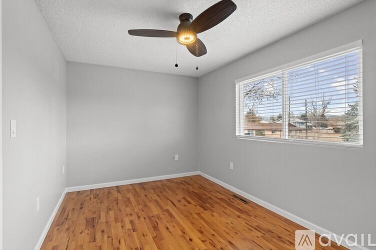 A room with a ceiling fan and a window with blinds.