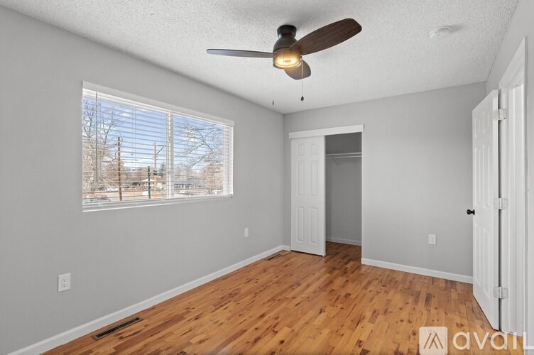 A room with a ceiling fan and a window overlooking a snowy landscape.