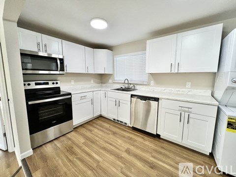 A kitchen with white cabinets and wooden floors.