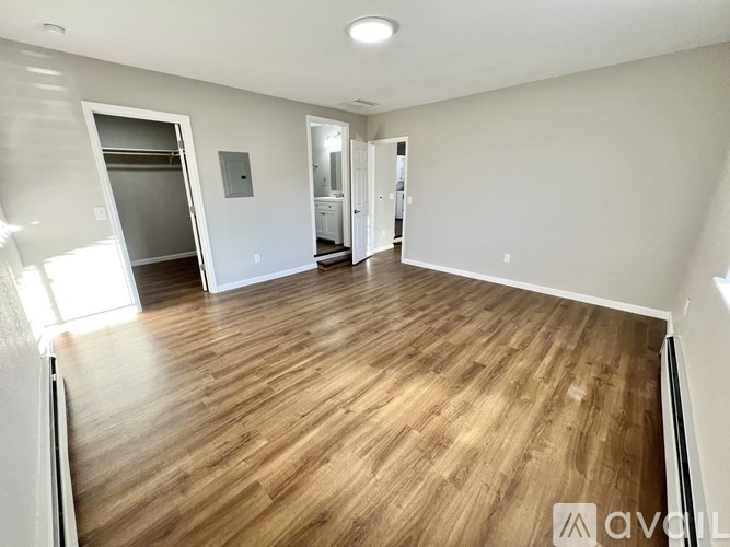 A spacious room with wooden flooring and white walls.