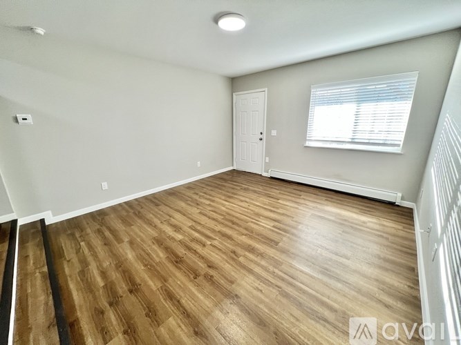 A room with wooden flooring and a window with blinds.