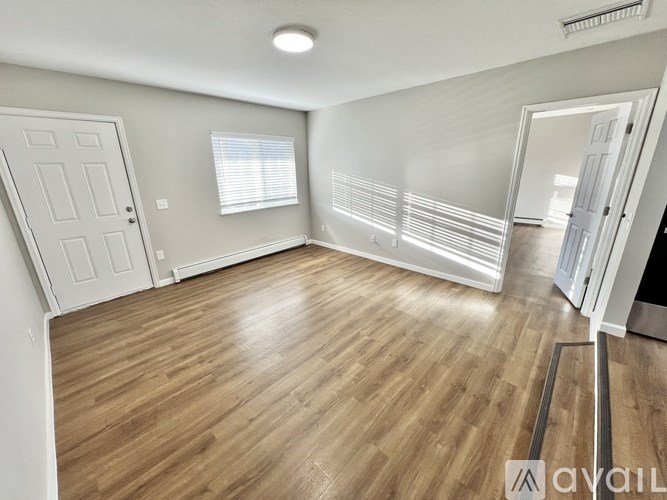 A room with wooden flooring and a white door.