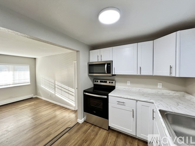 A kitchen with white cabinets and a wooden floor.