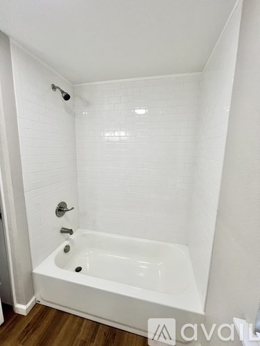 A white bathroom with a white tub and white tiles.