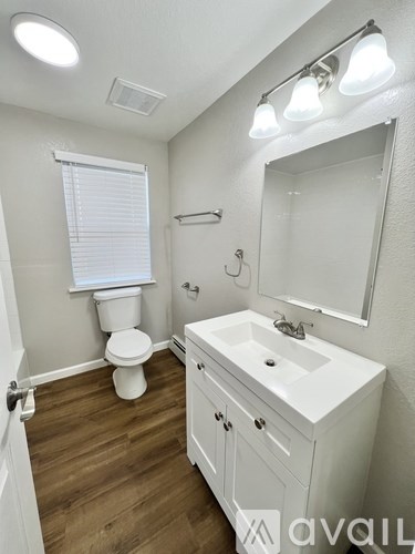 A white bathroom with wood flooring and a white sink.
