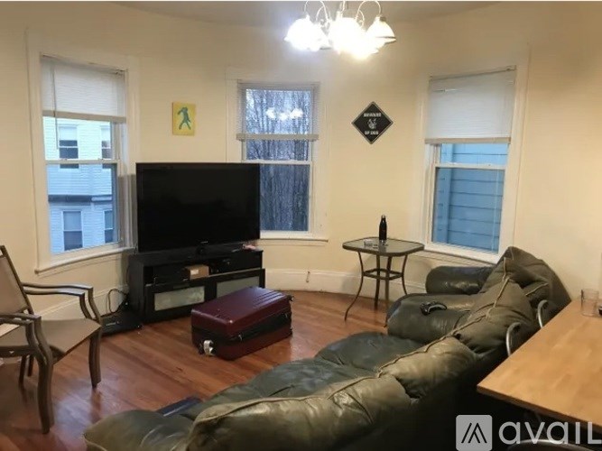 A living room with a television, a chair, a sofa, and a coffee table.