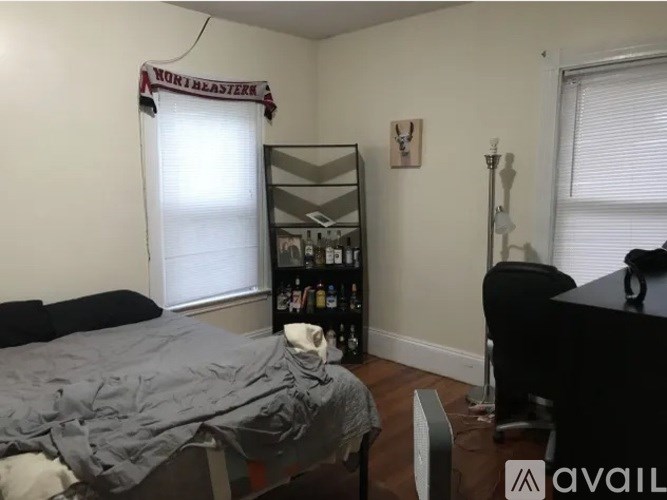 A room with a bed, a desk, and a window with blinds.