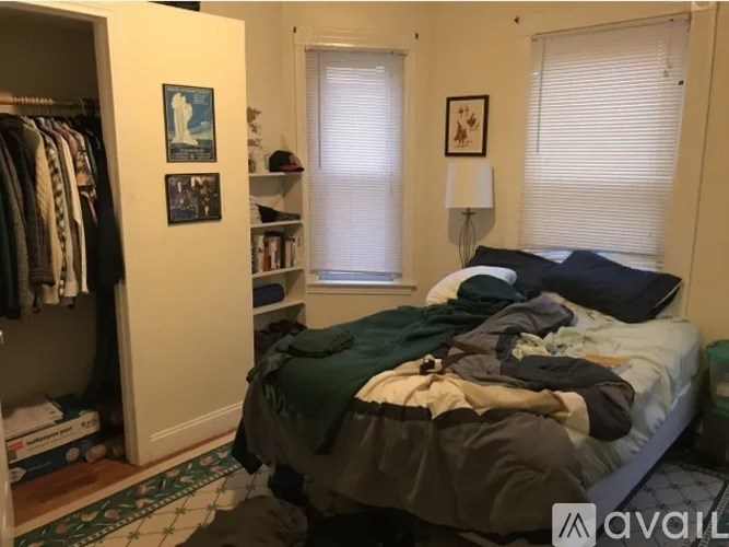 A bedroom with a bed, a wardrobe, and a window with blinds.