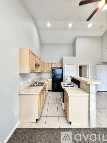 A kitchen with wooden cabinets and a black refrigerator.