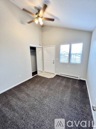 A room with a ceiling fan and carpeted floor.