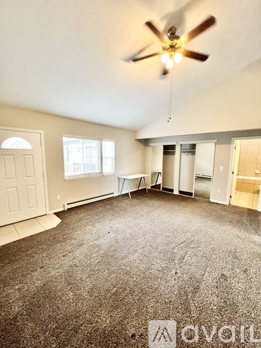 A room with a ceiling fan and carpeted floor.