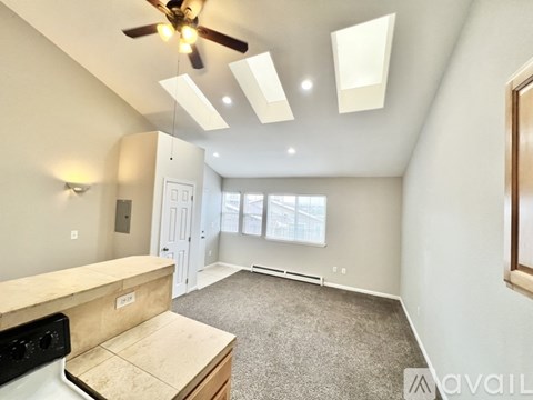 A spacious room with a kitchen island and a ceiling fan.