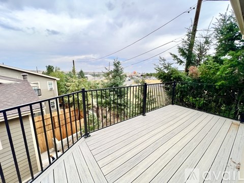 A wooden deck with a black railing and a house in the background.