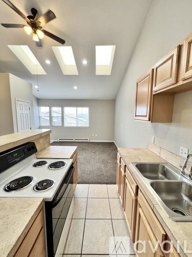 A kitchen with a stove, sink, and ceiling fan.
