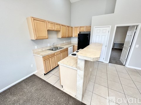 A kitchen with a black fridge and wooden cabinets.