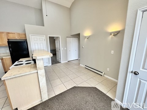 A kitchen with a black fridge, white cabinets, and a black stove top oven.