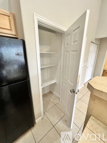 A black refrigerator is in a kitchen with a white door.