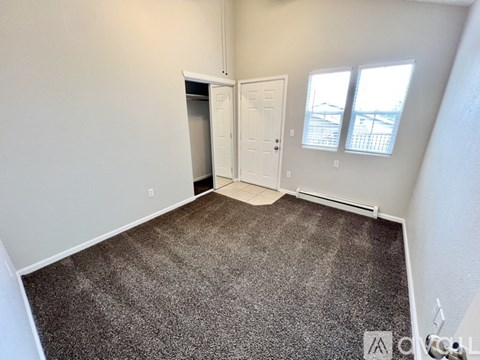 A carpeted room with a door and a window.