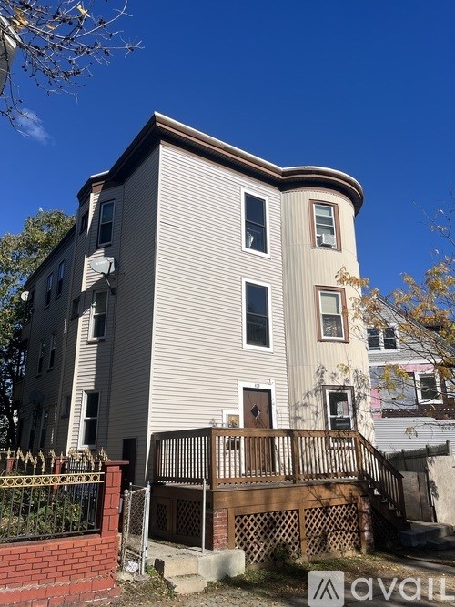 A house with a brown fence and a sign that says "avail" in front of it.