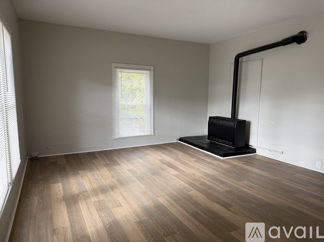 A room with wooden flooring and a black fireplace.