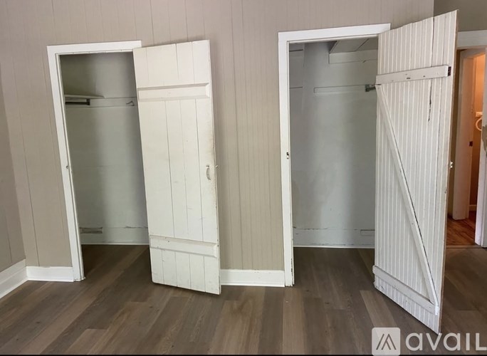Three white doors in a room with wooden floors.