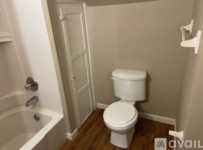 A white toilet in a small bathroom with a bathtub.