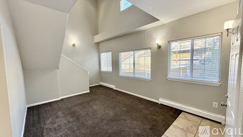 A spacious room with a carpeted floor and a staircase leading to another level.