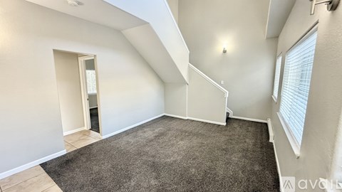A room with a carpeted floor and a window with blinds.