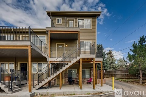 A modern two-story apartment building with a balcony and stairs leading to the upper floor.