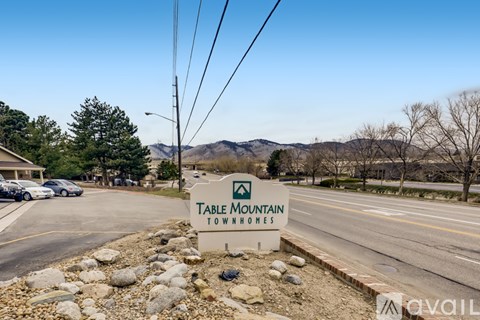 A sign for Table Mountain Townhomes is in the foreground with a mountainous background.