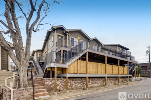A modern two-story house with a balcony and a tree in front.