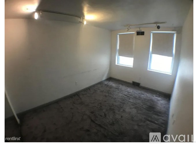 A room with a wooden floor and two windows.