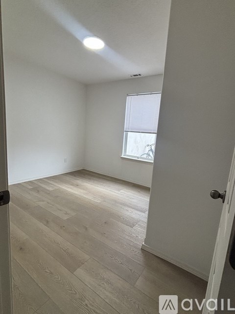 A room with wooden flooring and a window with blinds.