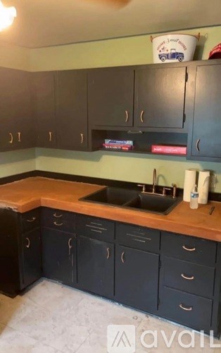 A kitchen with black cabinets and a wooden countertop.