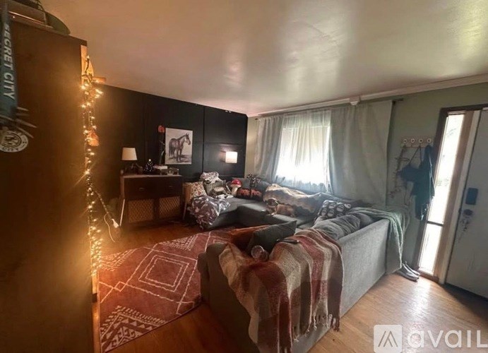 A room with a bed, a couch, and a table with a lamp on it.