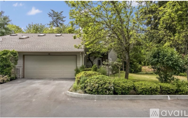 A house with a garage and a tree in front.