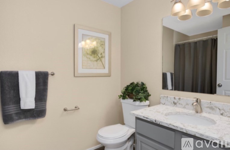 A bathroom with a toilet, sink, mirror, and a potted plant.