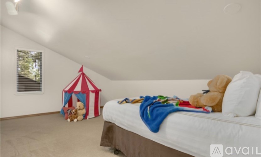 A bedroom with a bed, a teddy bear, and a play tent.