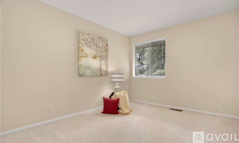 A room with a red pillow and a painting on the wall.