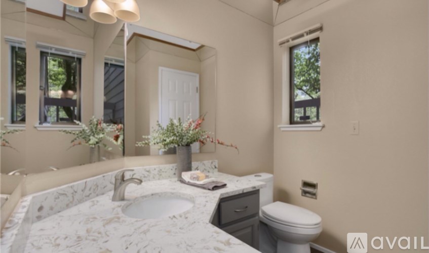 A bathroom with a marble countertop and a large mirror.