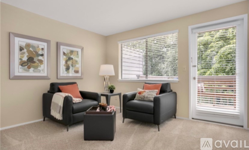 A living room with two black leather chairs, a coffee table, and two framed pictures on the wall.