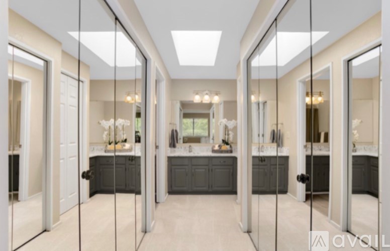 A bathroom with a vanity and a mirrored wall.