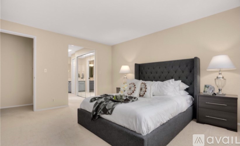 A bedroom with a large bed, nightstand, and lamp.