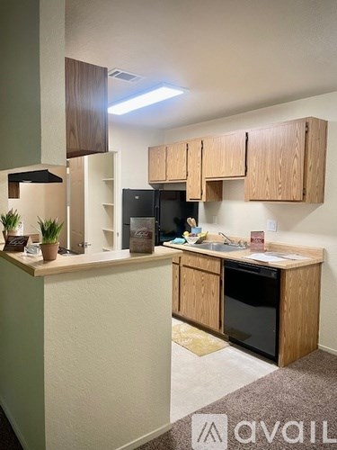 A kitchen area with wooden cabinets and a black fridge.