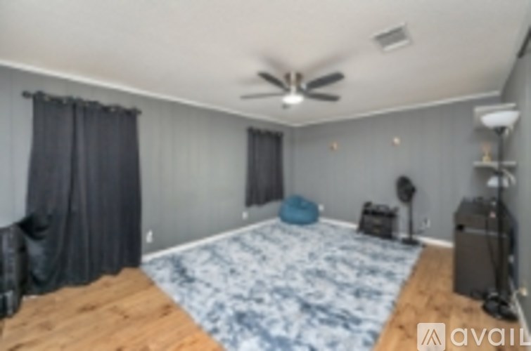 A bedroom with a ceiling fan and a bed with a blue patterned cover.