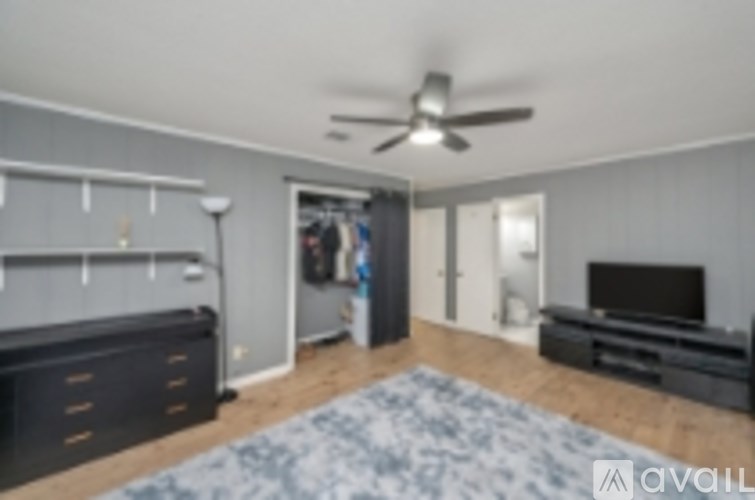 A room with a ceiling fan and a blue rug on the floor.