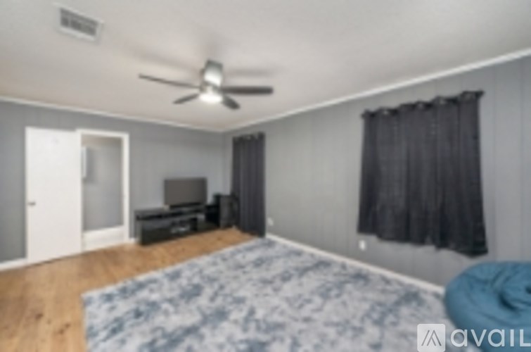 A room with a ceiling fan and a blue rug on the floor.