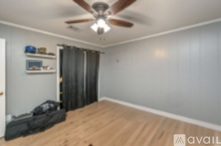 A room with a ceiling fan and a suitcase on the floor.
